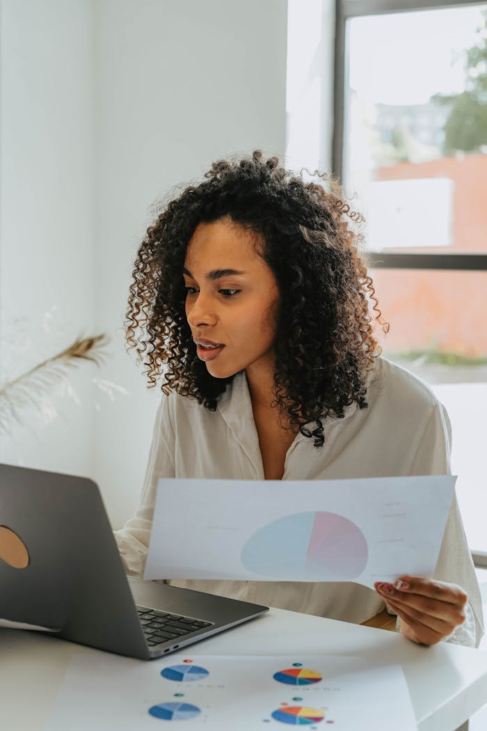 home-hero Confident woman working on a laptop, analyzing business charts in a bright office setting.